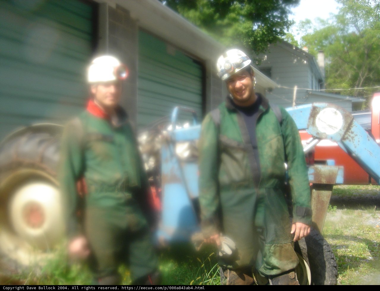 Two workers in green coveralls inspecting a tire