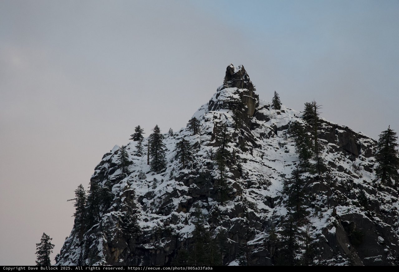 Snow-Dusted Rocky Pinnacle Among Evergreen Trees at Dusk