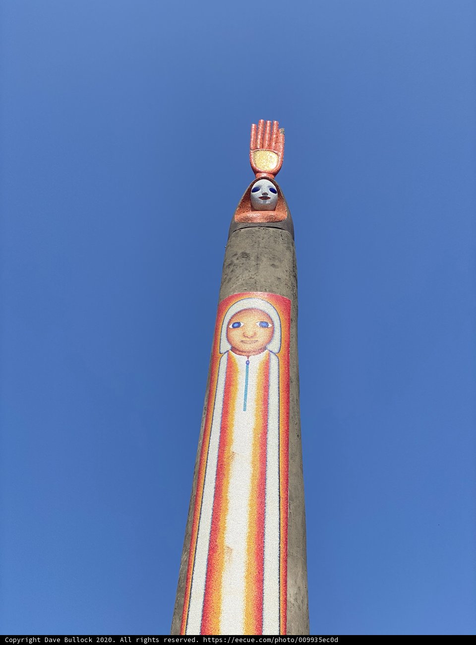 Painted Face Totem Pole Against Clock Tower
