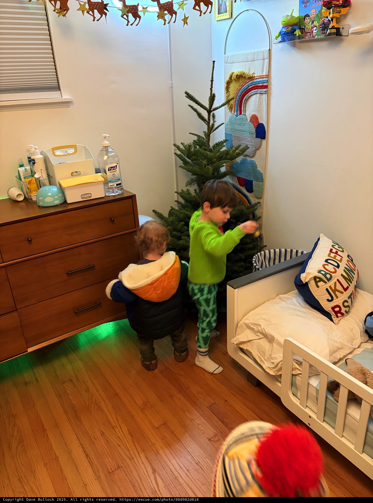Two Children Decorating Christmas Tree in Bedroom