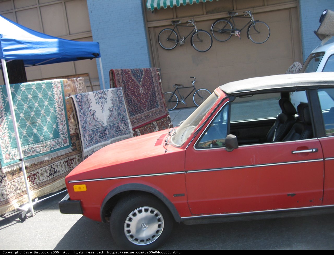 Red Car Parked in Front of Blue Tent