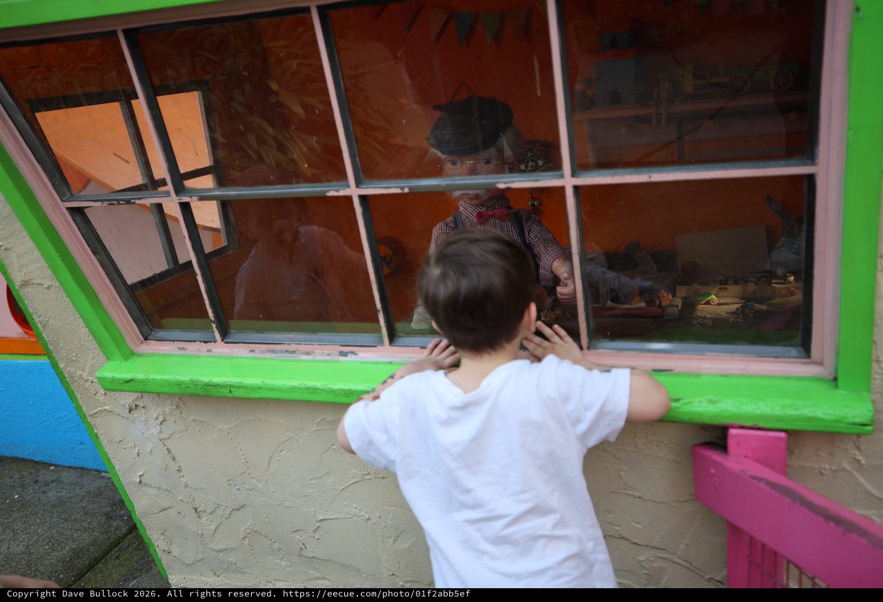 Child Peering into Window of Colorful Playhouse