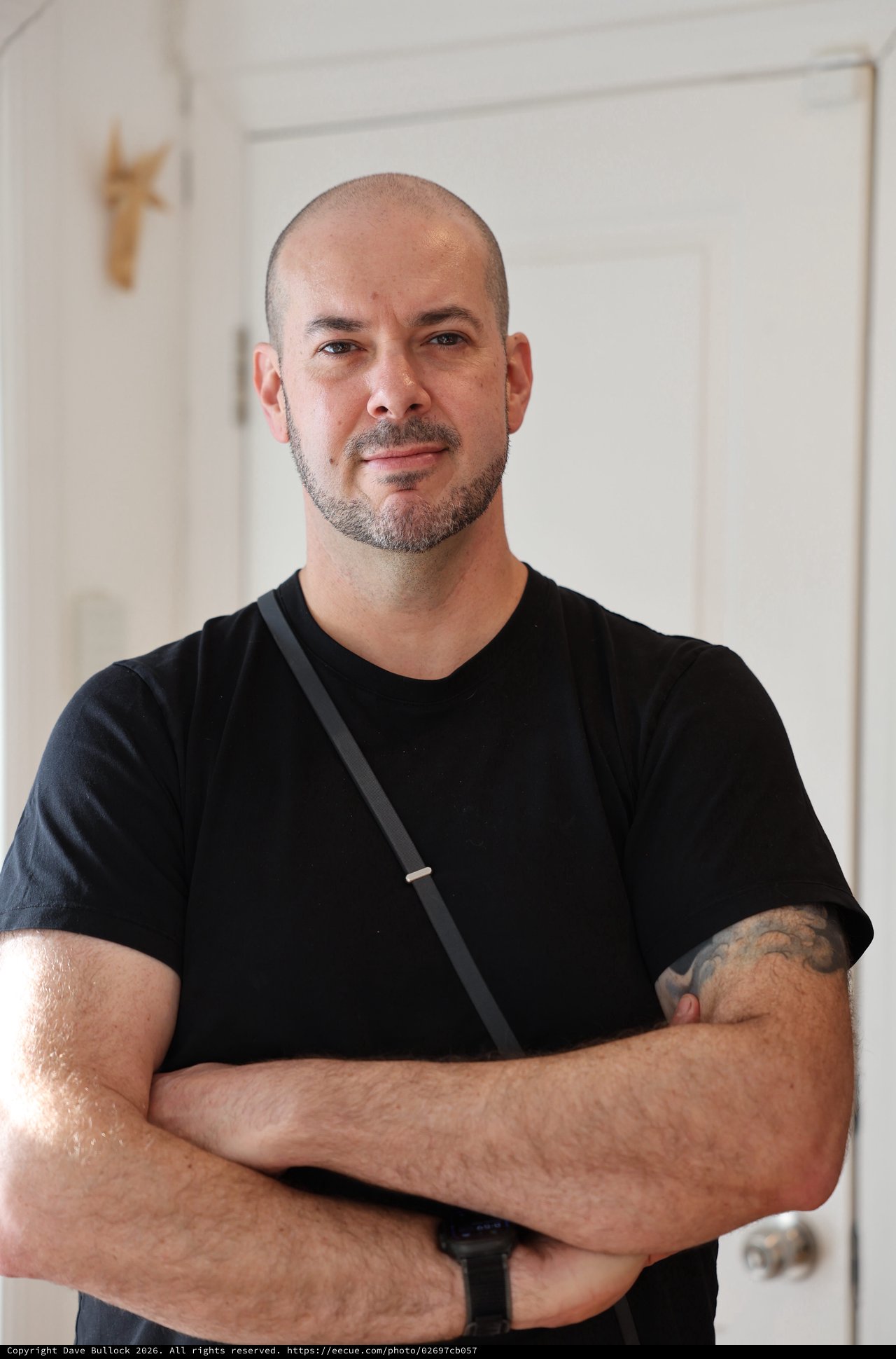 Confident Portrait of Bald Man with Tattoo in Modern Interior