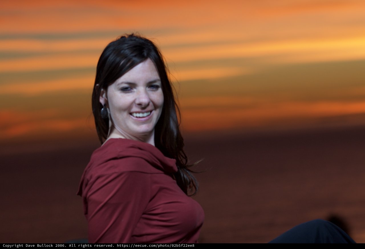 Smiling Woman Glowing Against a Fiery Sunset Sky