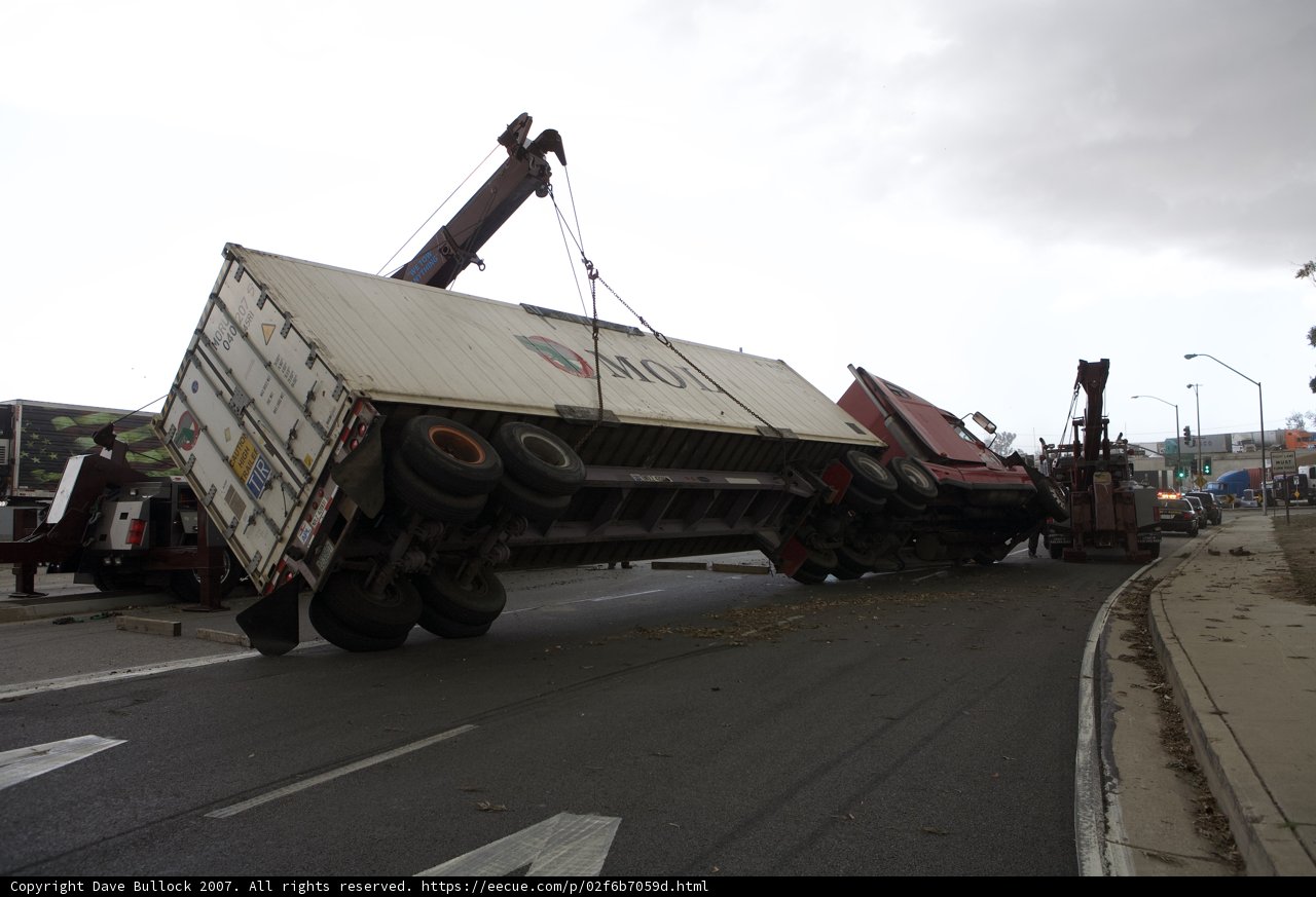 Crane lifts overturned truck on busy road