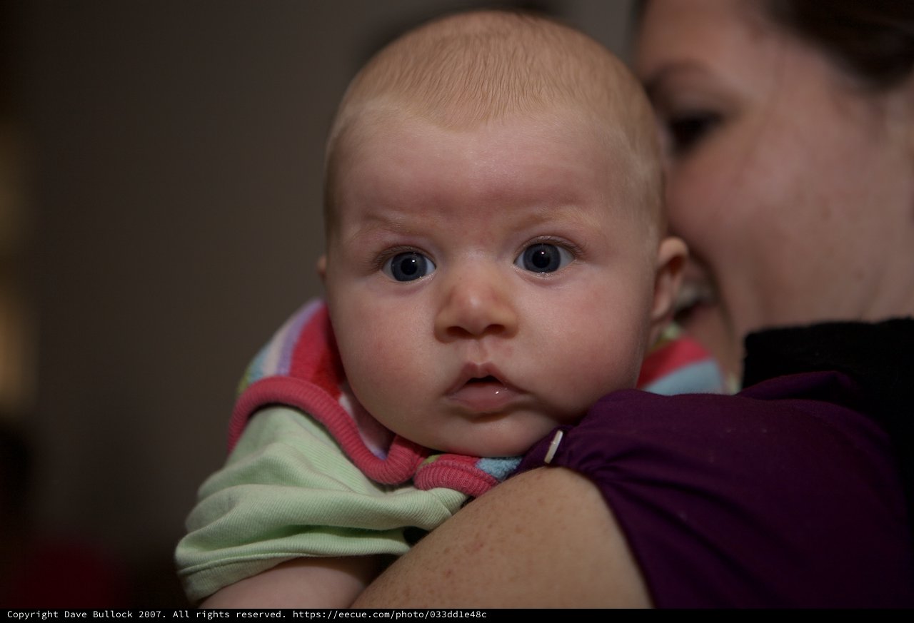 Wide-Eyed Infant Gazing Curiously Over Shoulder