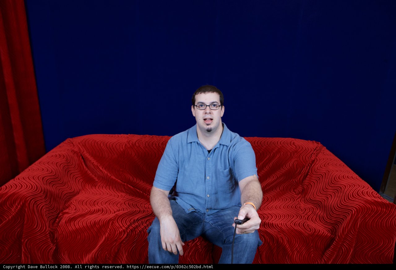 Dave B lounges on a red velvet sofa