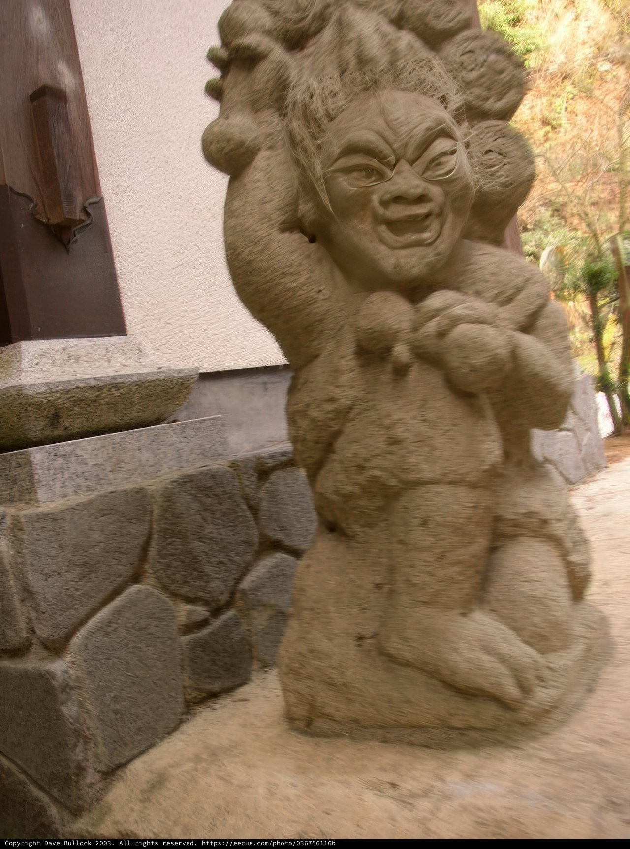 Smiling Statue on Stone Wall