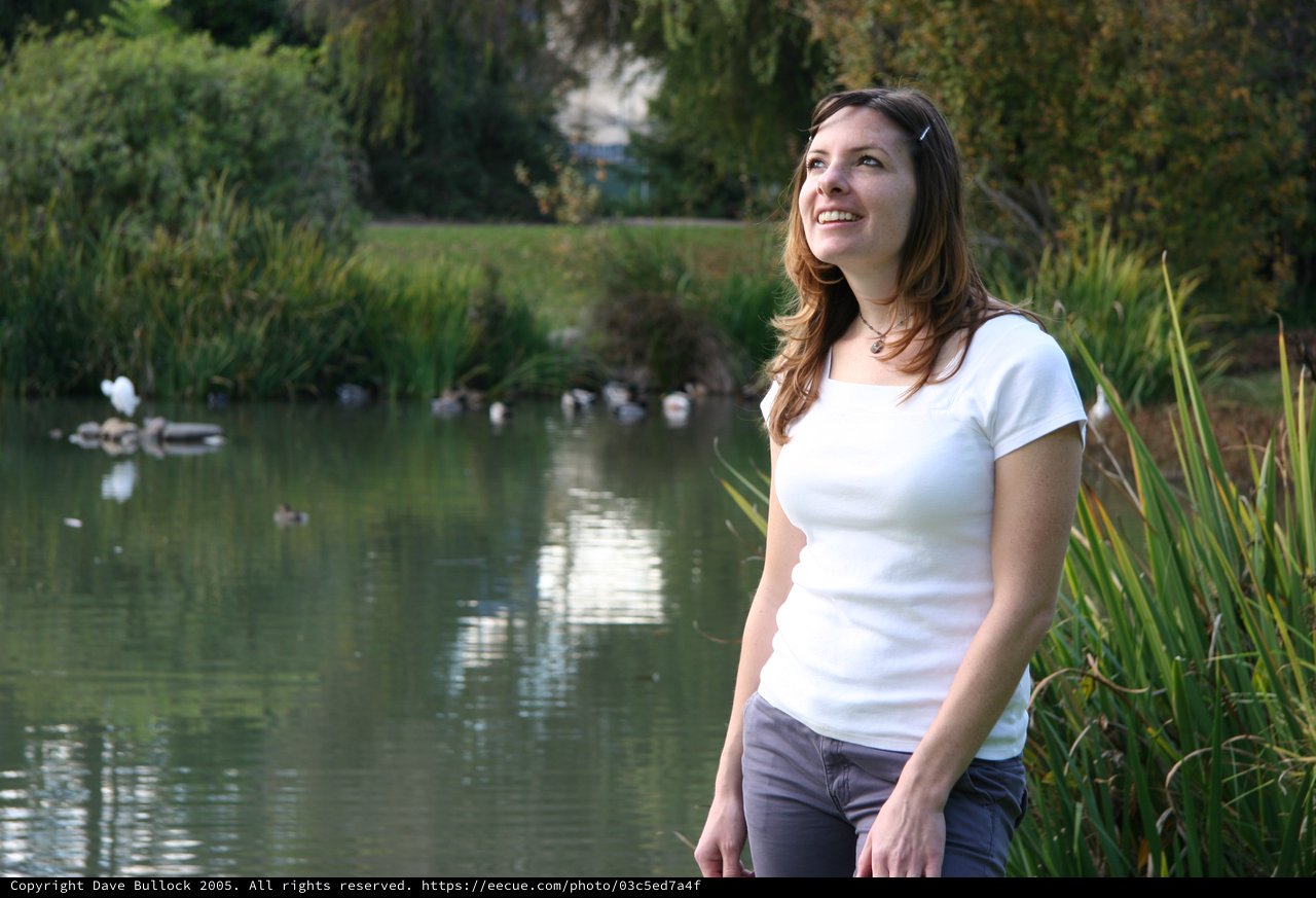 Woman Gazing Skyward by a Tranquil Park Pond