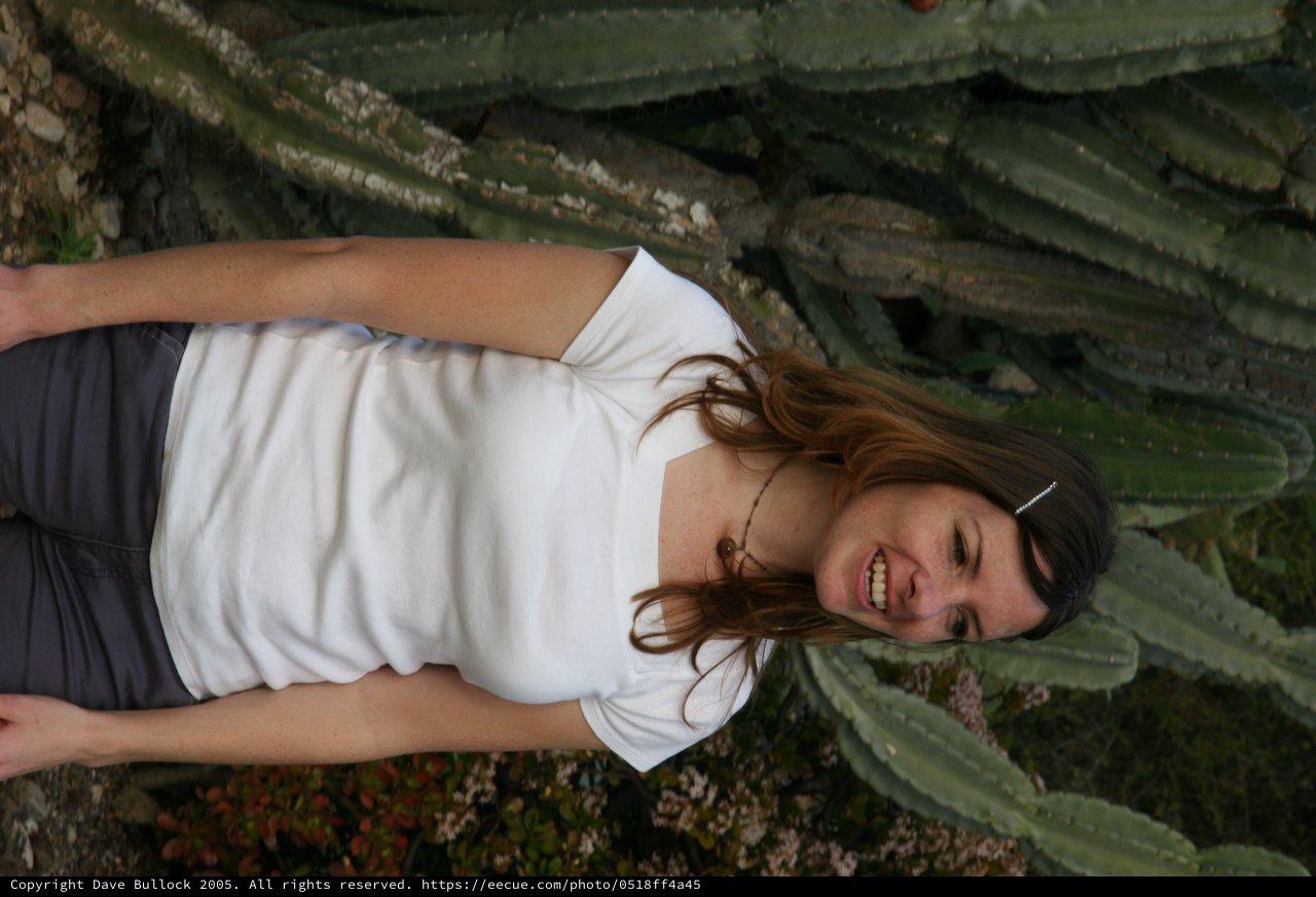 Smiling Woman Among Towering Cacti in Garden
