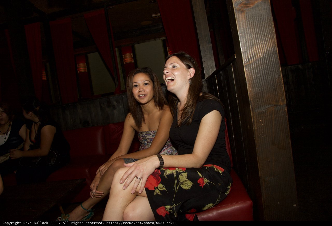 Two Women Laughing Together at a Dimly Lit Bar