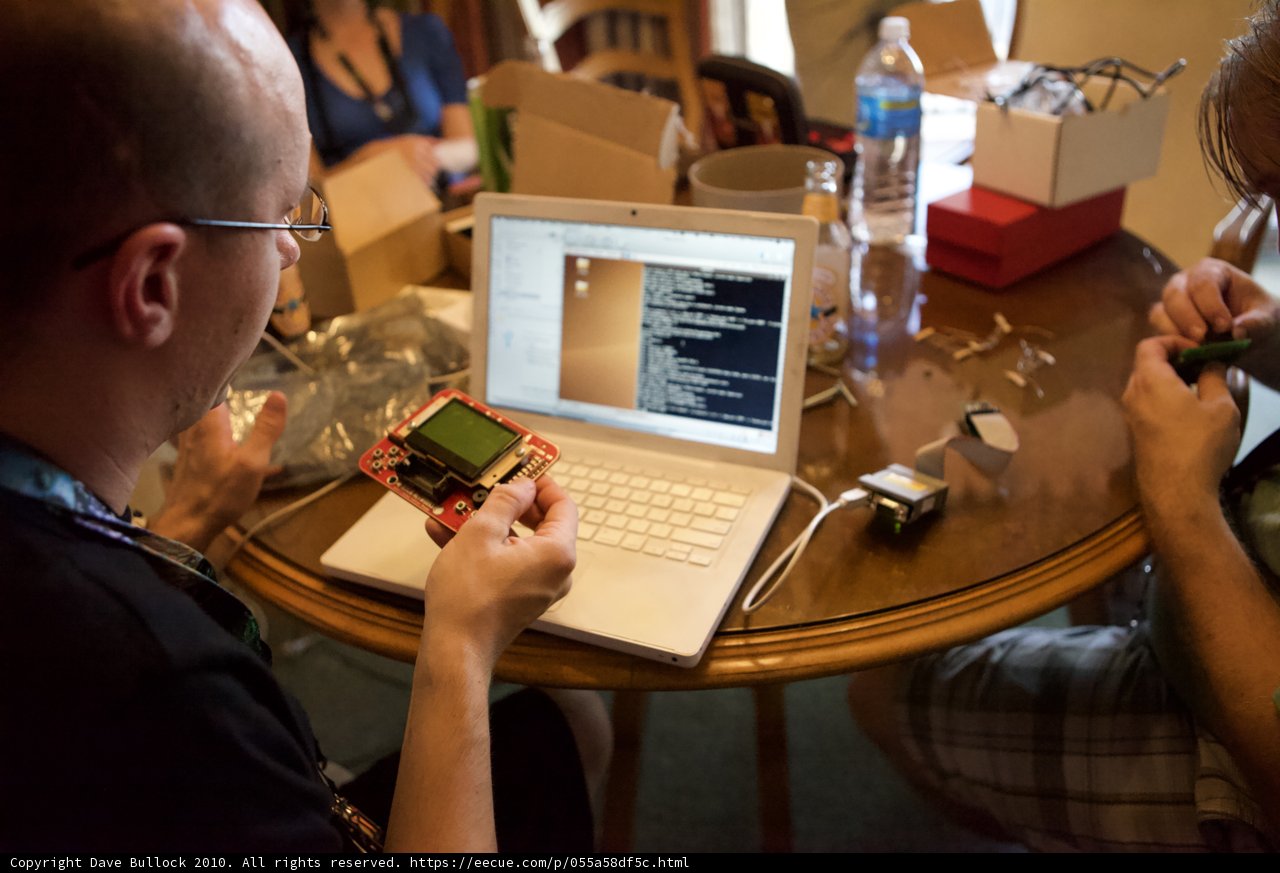 Collaborating on a Laptop Caption: Two individuals work together on a laptop computer, surrounded by furniture and consumer electronics. Their eyeglasses and fingers hover over the computer keyboard as they focus on the screen.