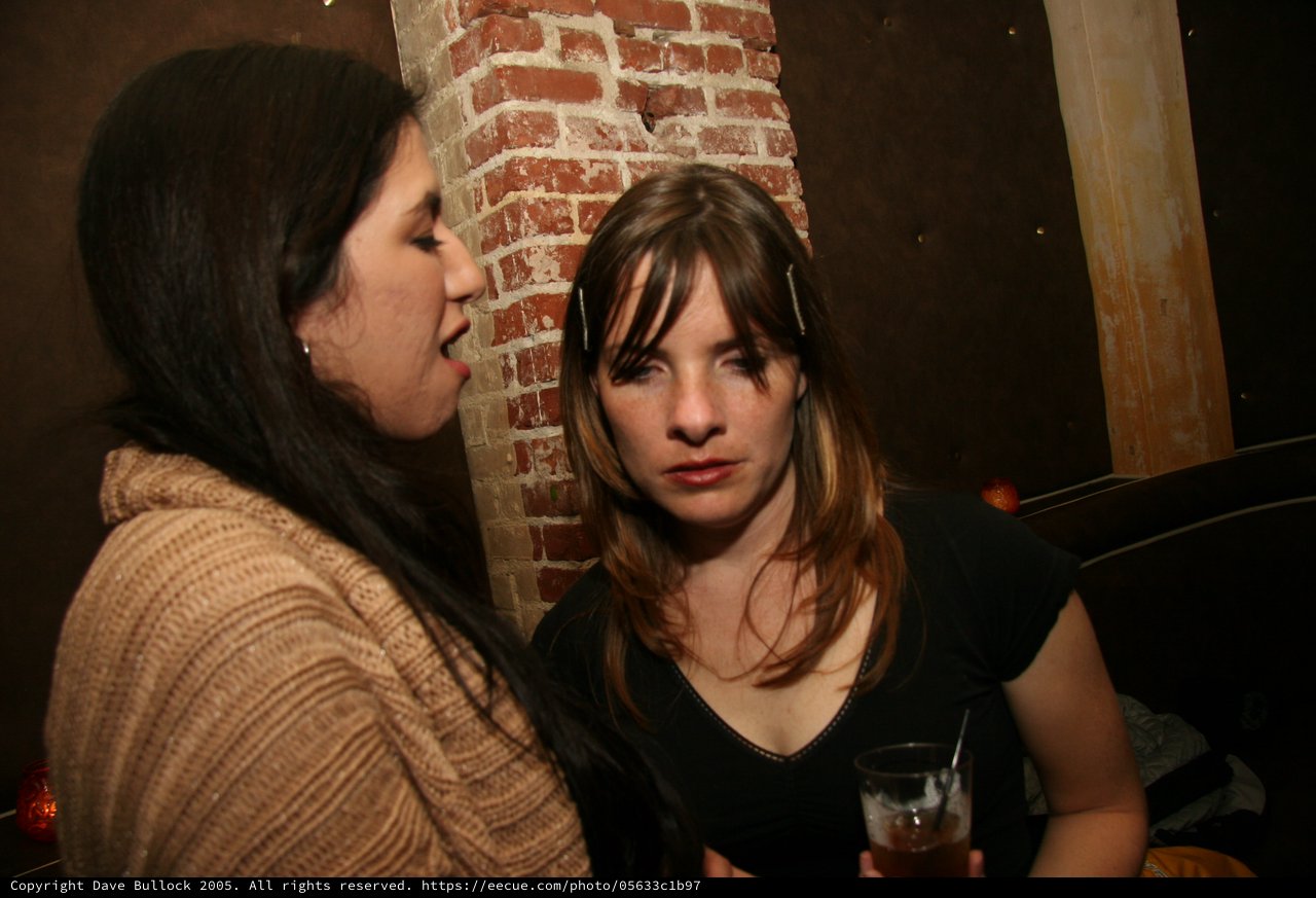 Two Women Conversing at a Dimly Lit Bar