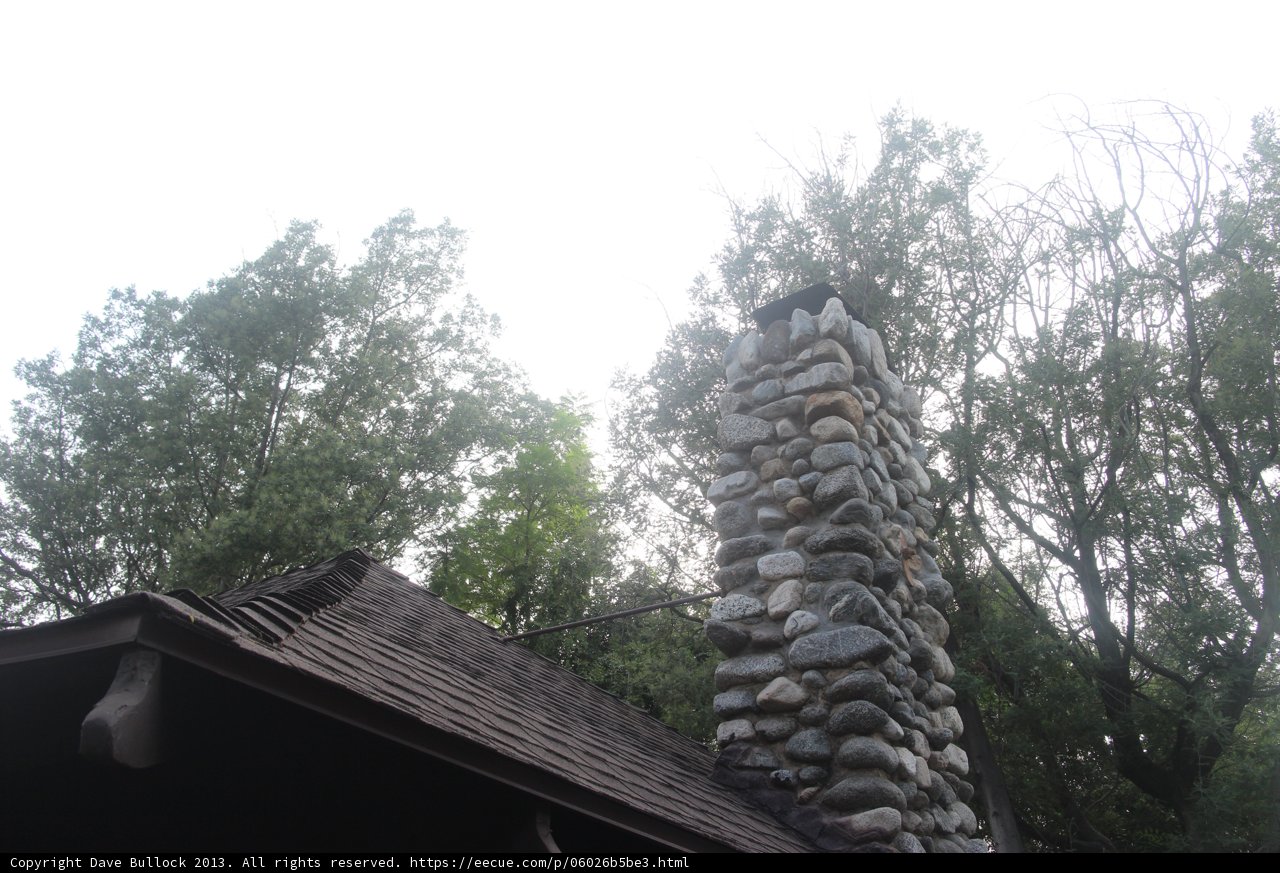 Slate-roofed stone chimney in rural setting