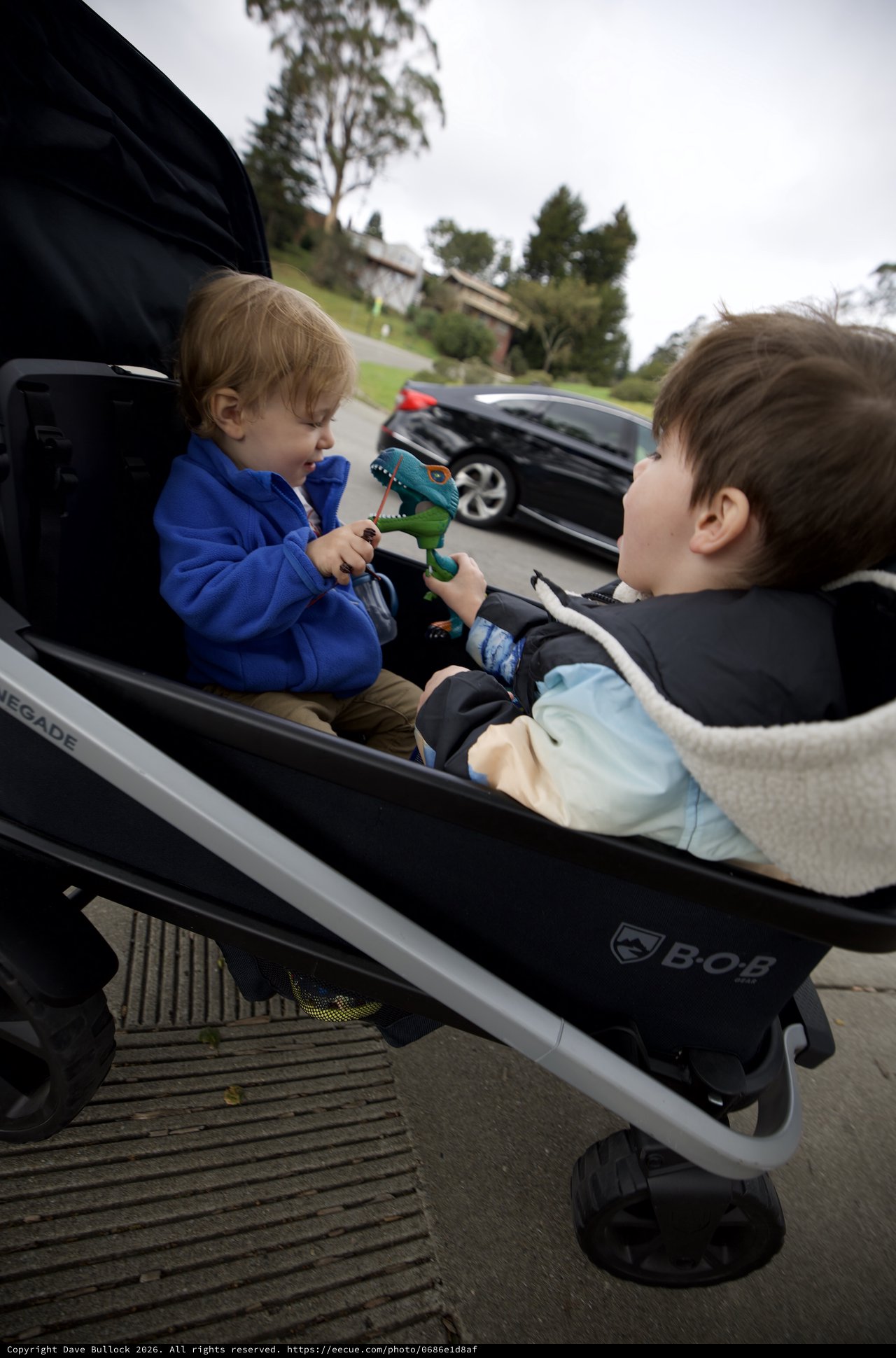 Two Young Children Sharing Toys in Double Stroller
