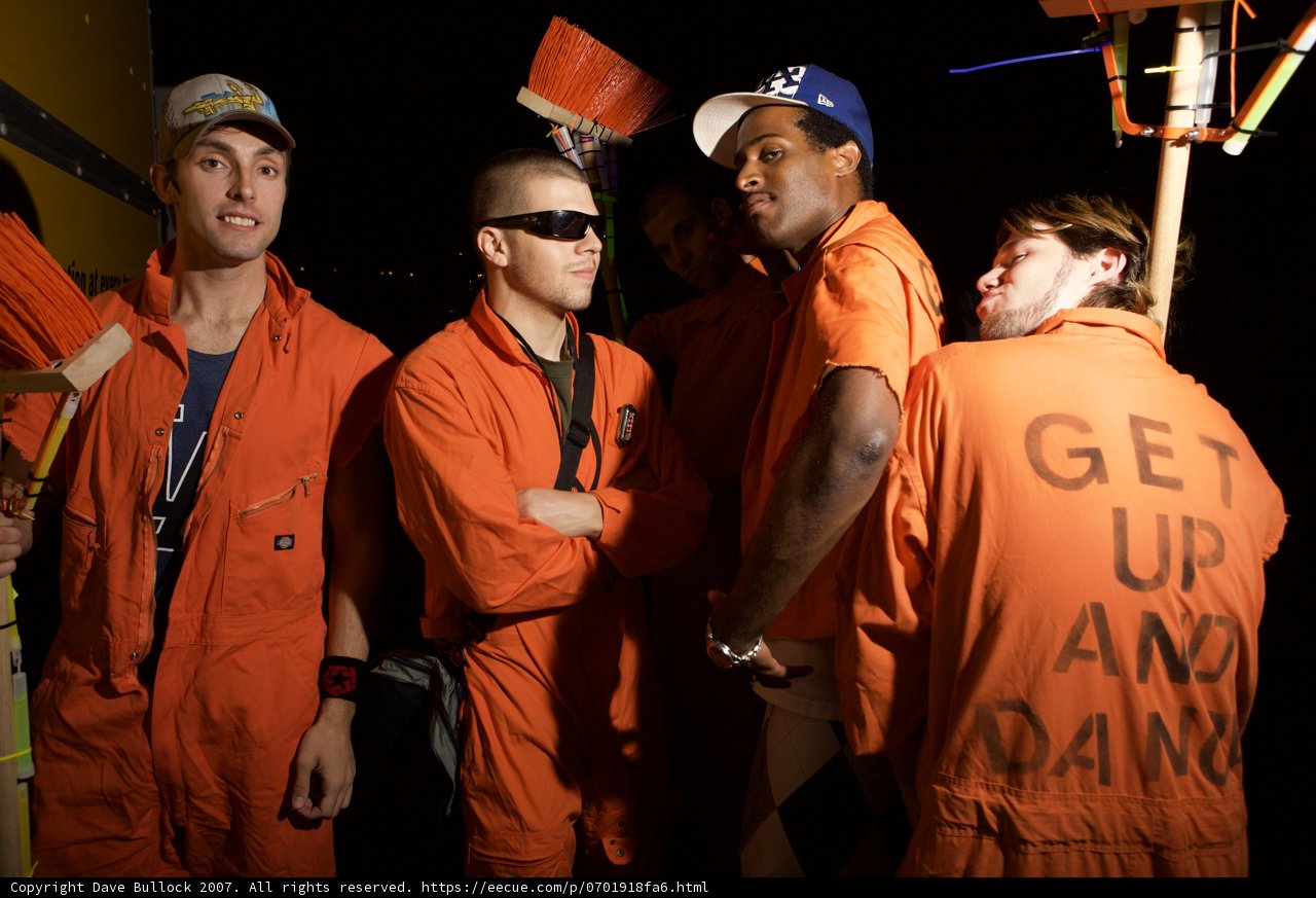 Group of Men in Orange Jumpsuits at Work Site