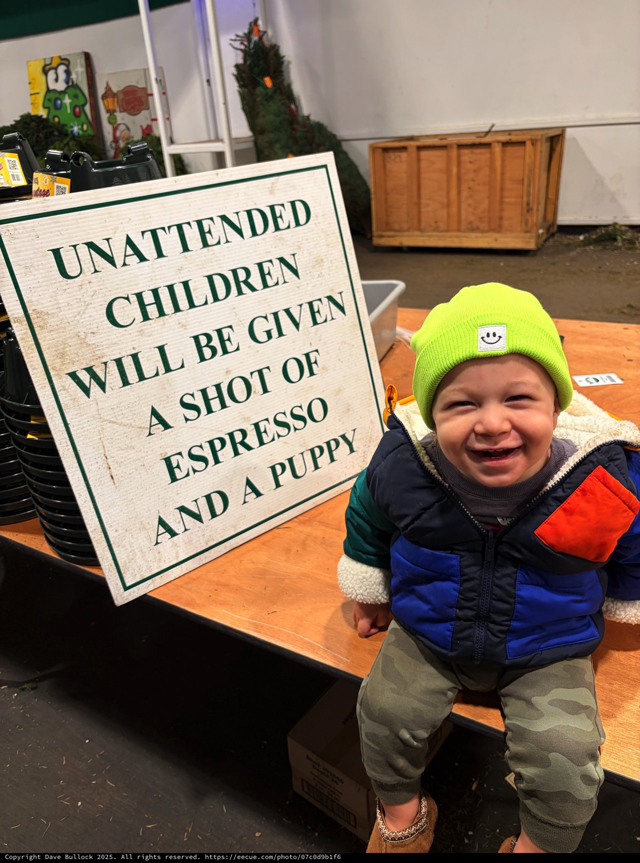 Joyful Toddler at Coffee Shop with Humorous Warning Sign