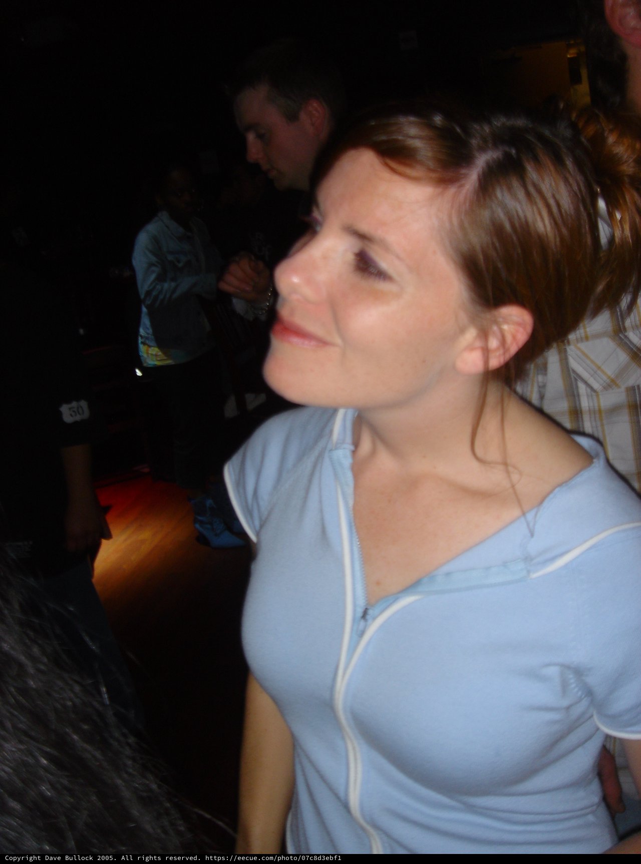 Woman Smiling Upward at Dimly Lit Venue