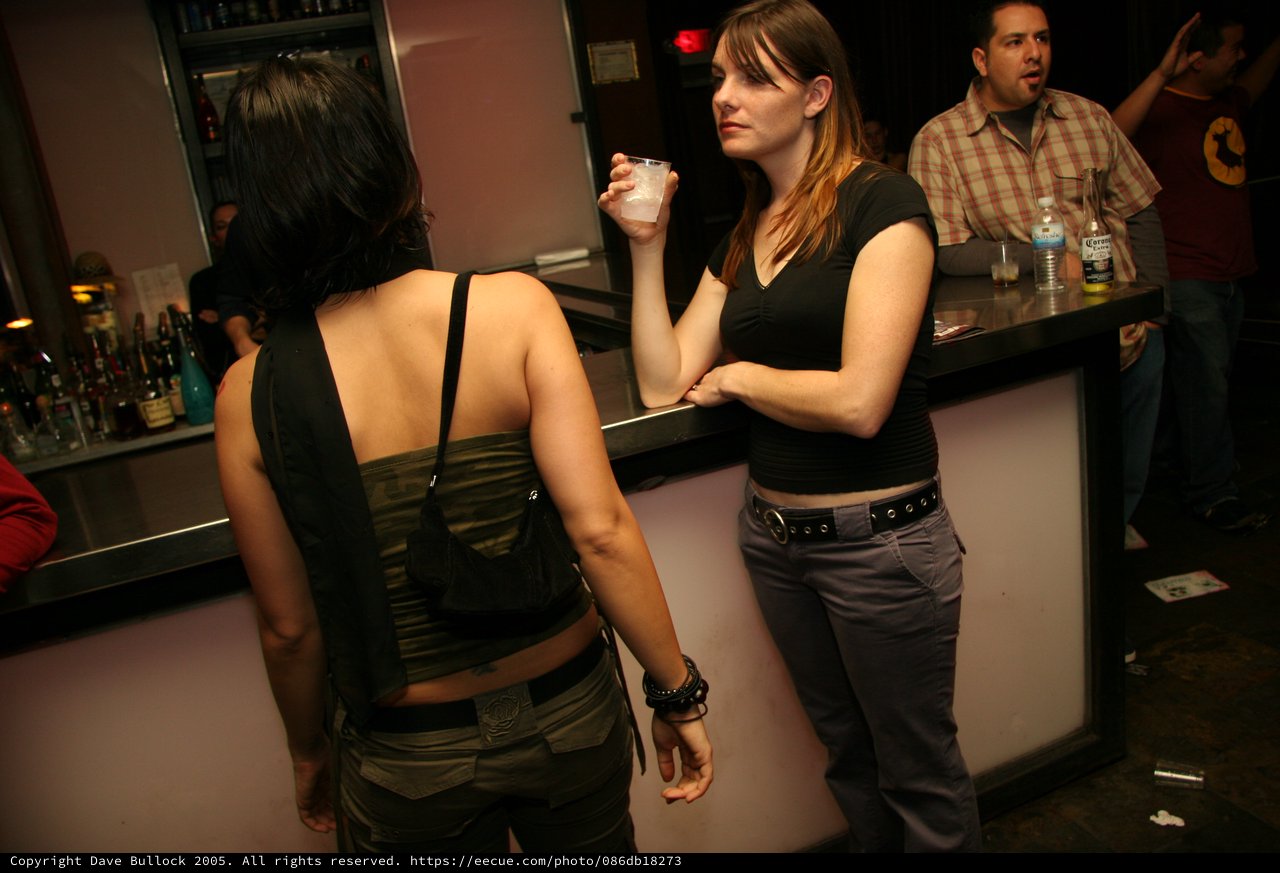 Two Women Conversing at a Dimly Lit Bar