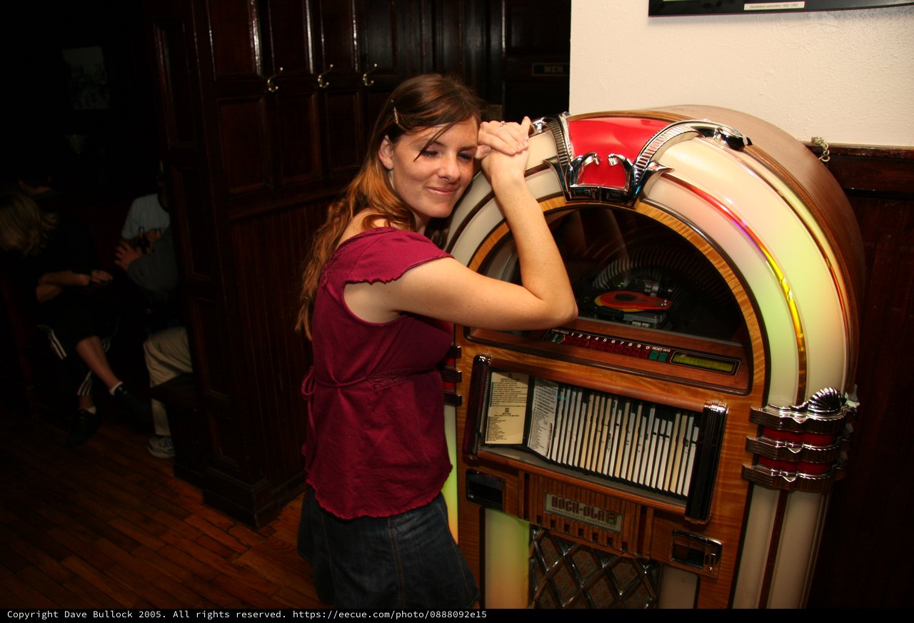 Young Woman Poses Playfully with Classic Jukebox