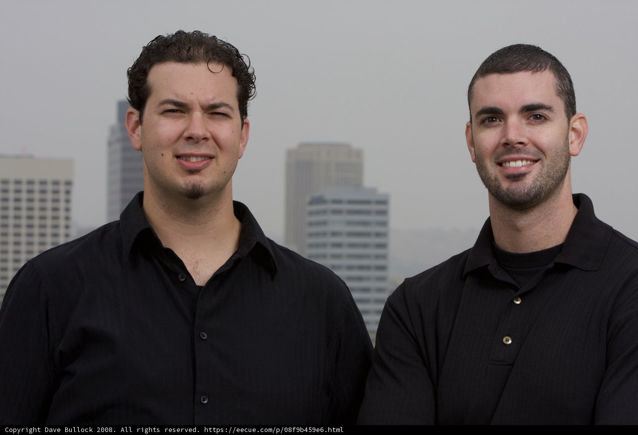 Two Men Posing in Front of a Skyscraper