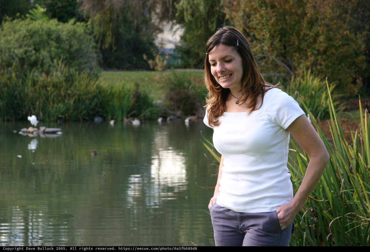 Woman Smiling by a Peaceful Park Pond