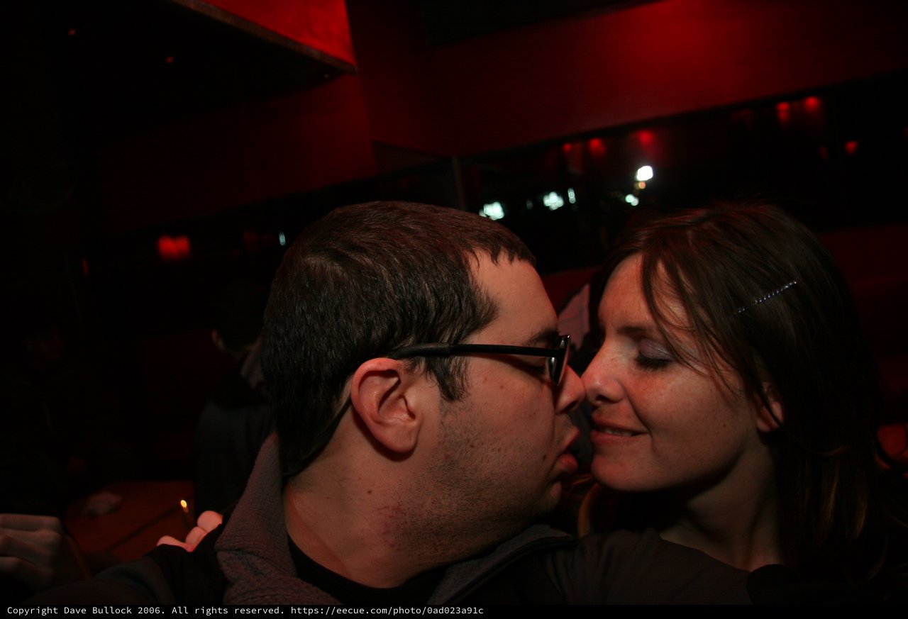 Intimate Moment: Couple Kissing in Dimly Lit Bar