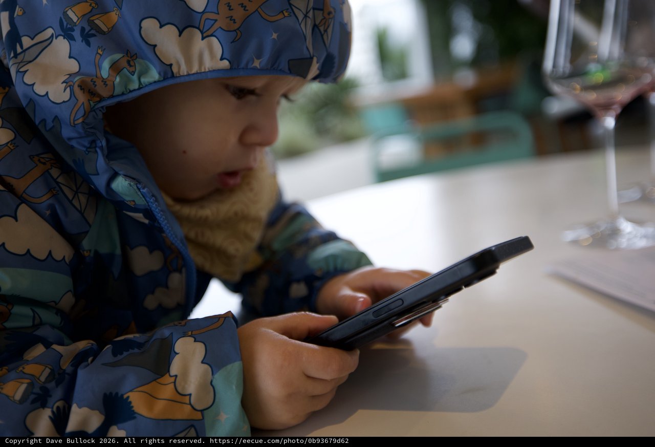 Young Child Engaged with Smartphone at Restaurant