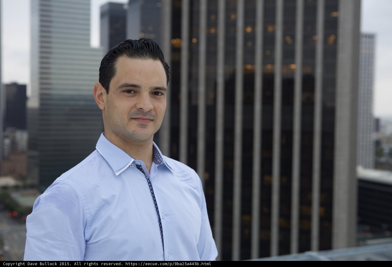 Blue Shirted Man Grinning in Front of City