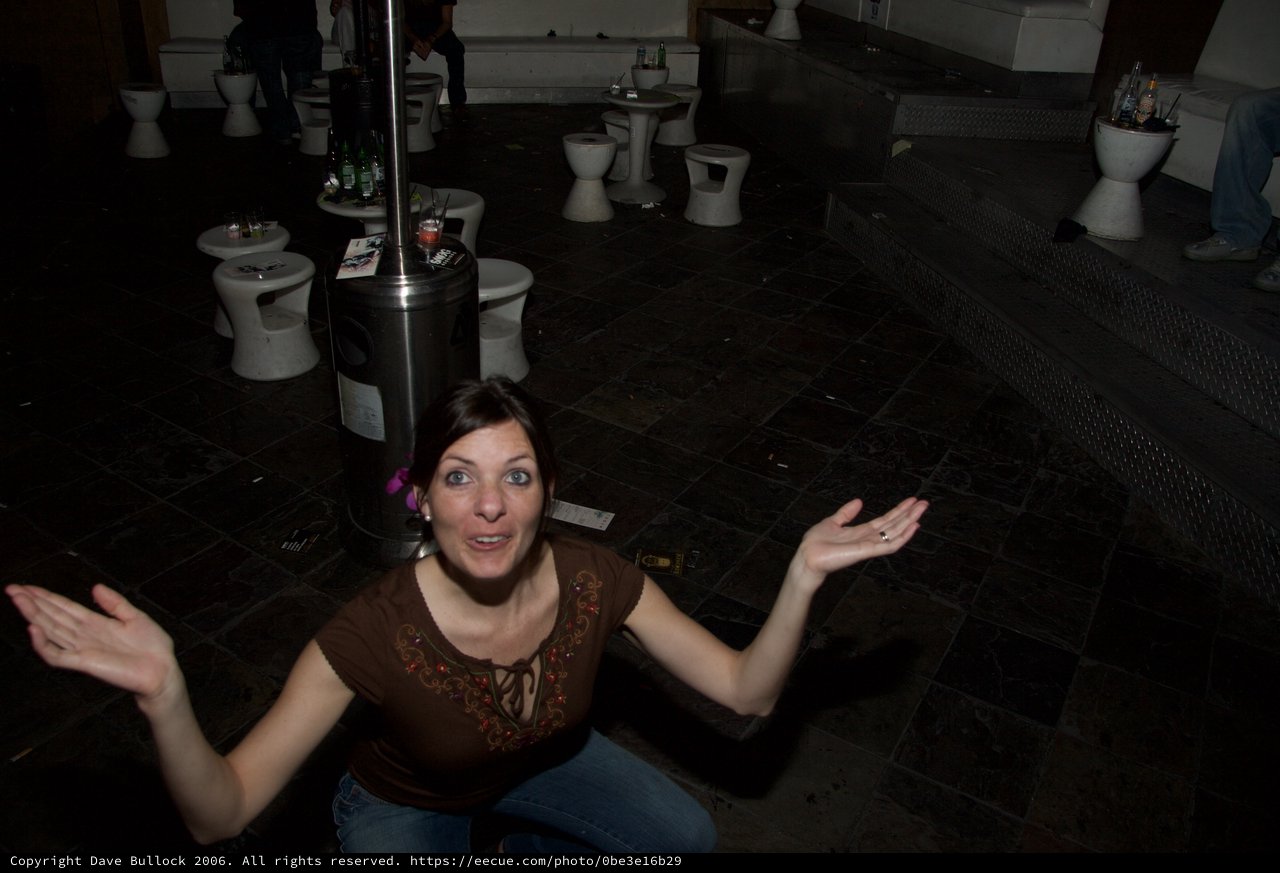 Woman Gestures Expressively in Dark Nightclub Venue