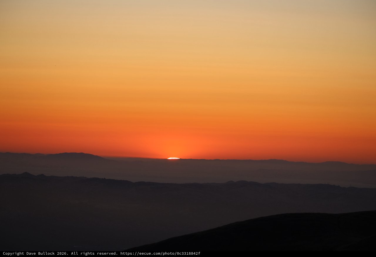 Last Light: Sun Dissolves Behind Distant Mountain Ridges