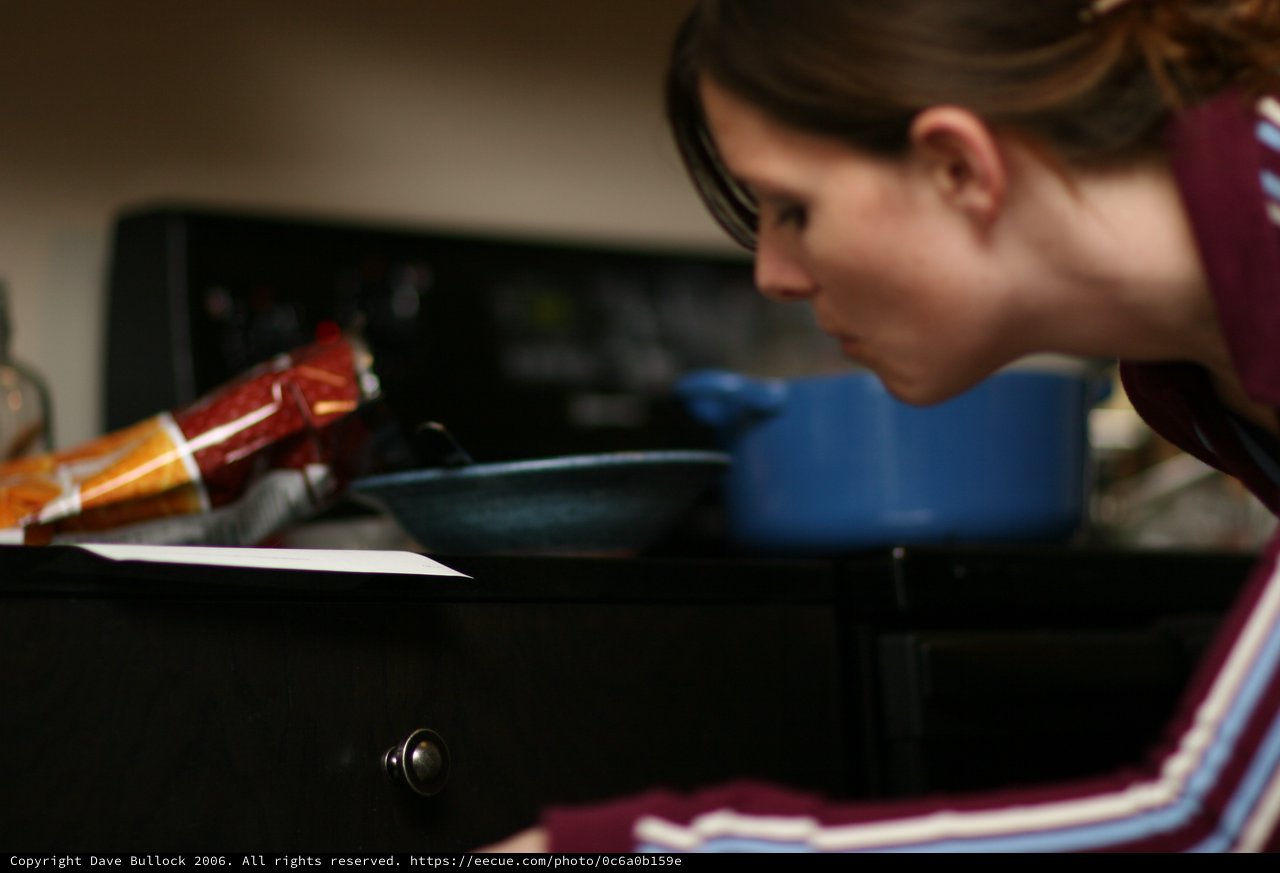 Woman Intently Reading Recipe at Kitchen Stove