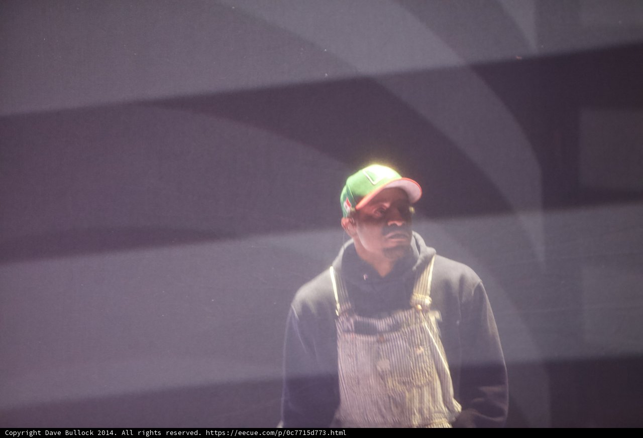 Man in Overalls Stands in Spotlight