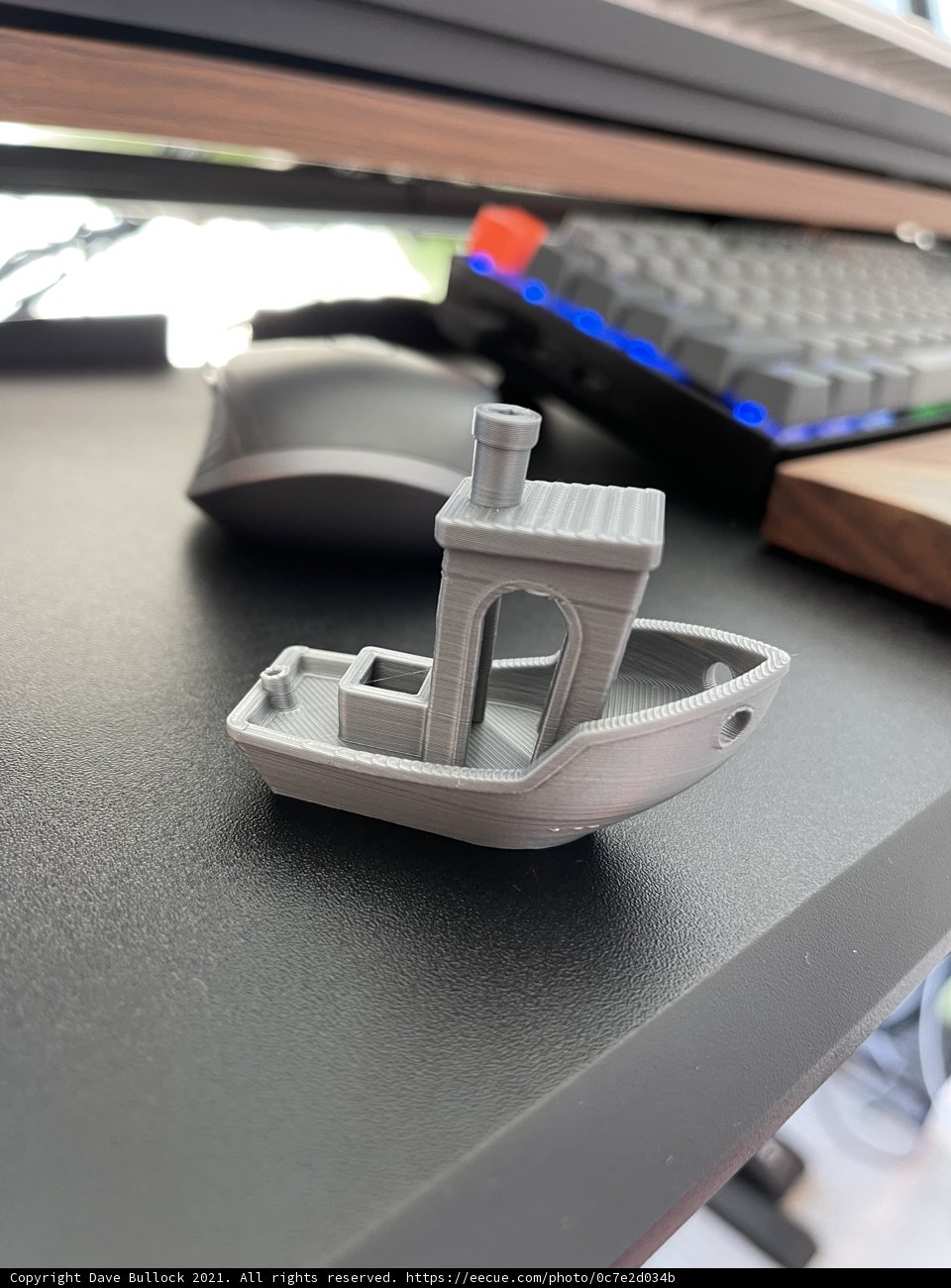 Miniature Boat for Scale Caption: A tiny boat sits peacefully on the desk next to a computer keyboard, offering a sense of whimsy and adding a unique touch to the workspace.