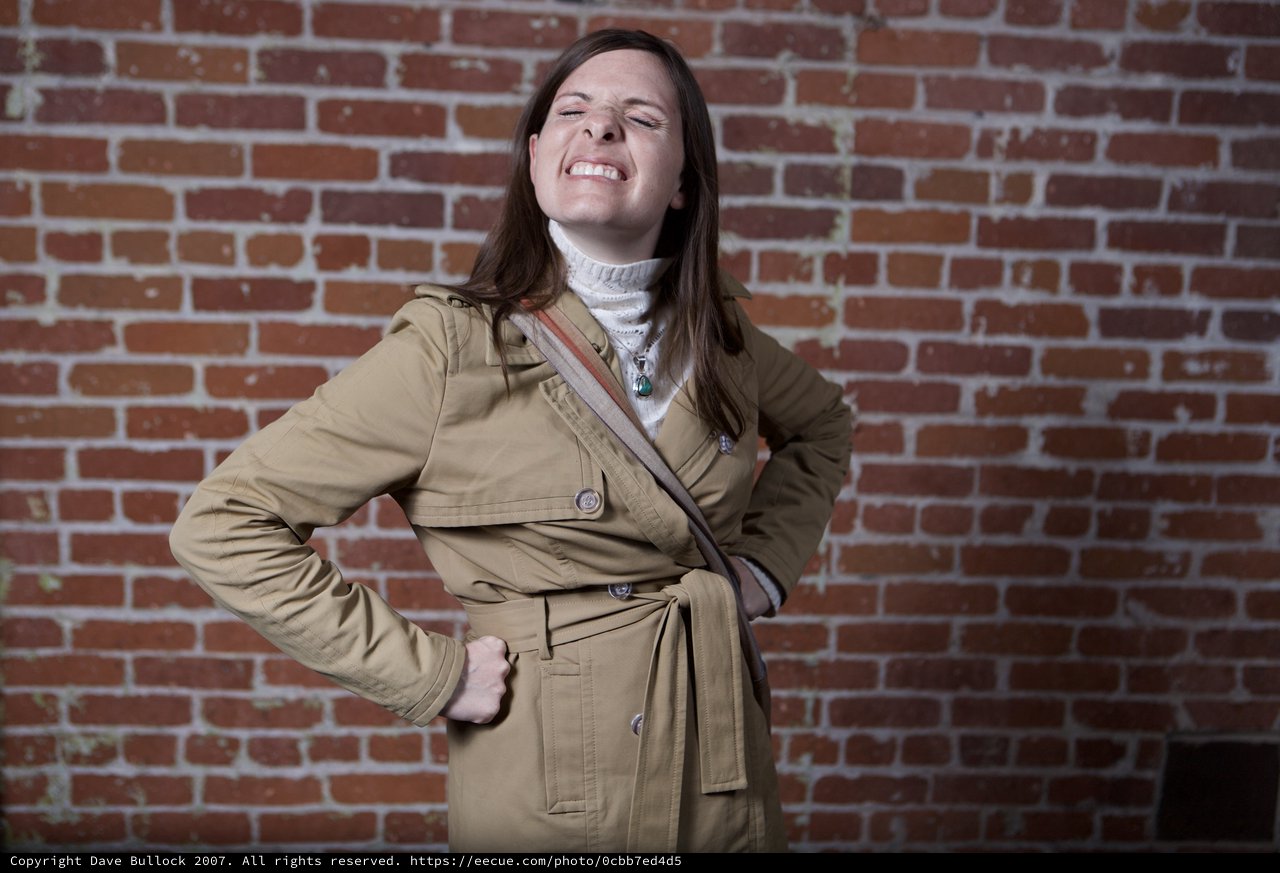 Playful Woman Strikes Pose Against Urban Brick Wall
