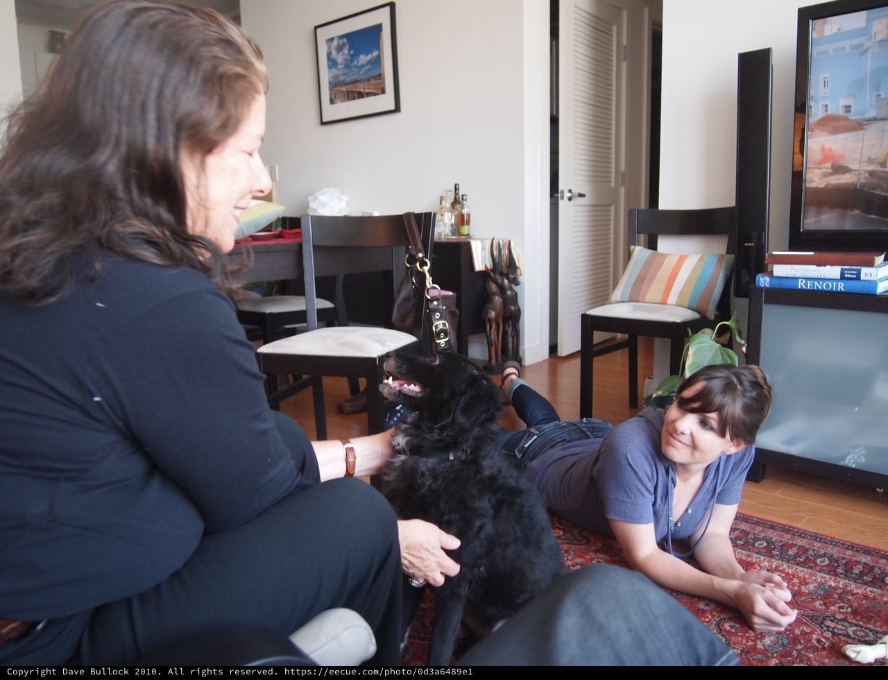 Two Women Bonding with Black Dog Indoors