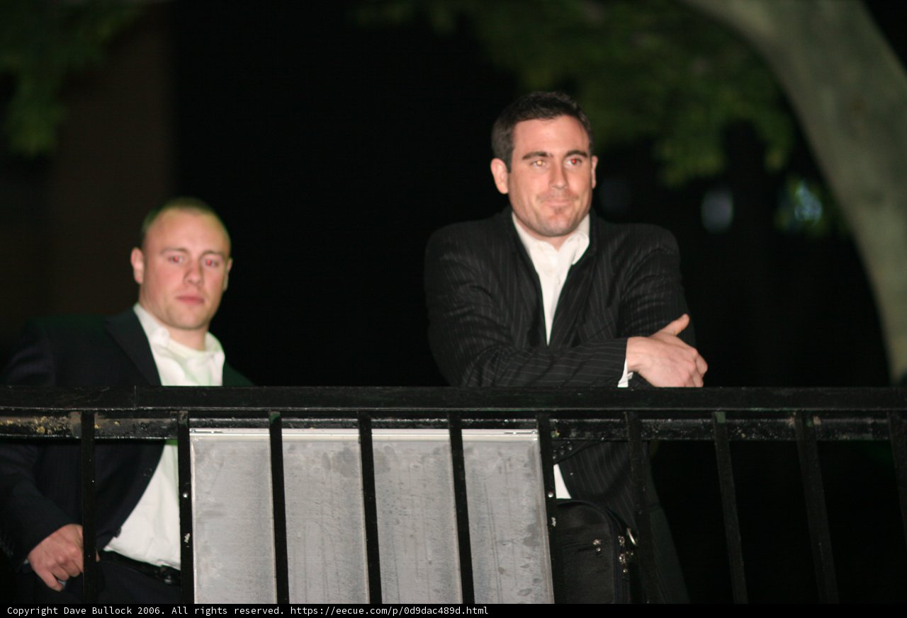 Two Men in Formal Wear Standing on Balcony