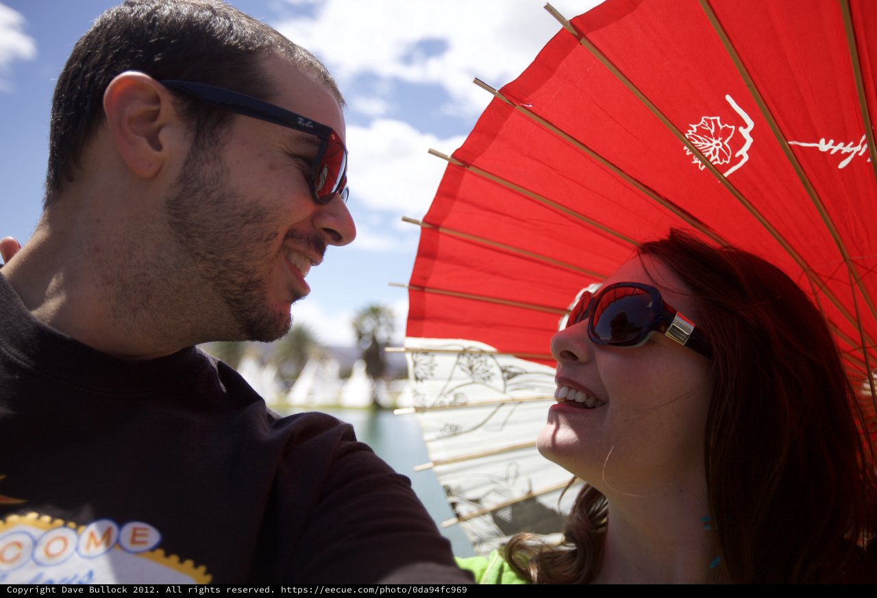 Couple Shares a Smile Under Red Parasol at Coachella