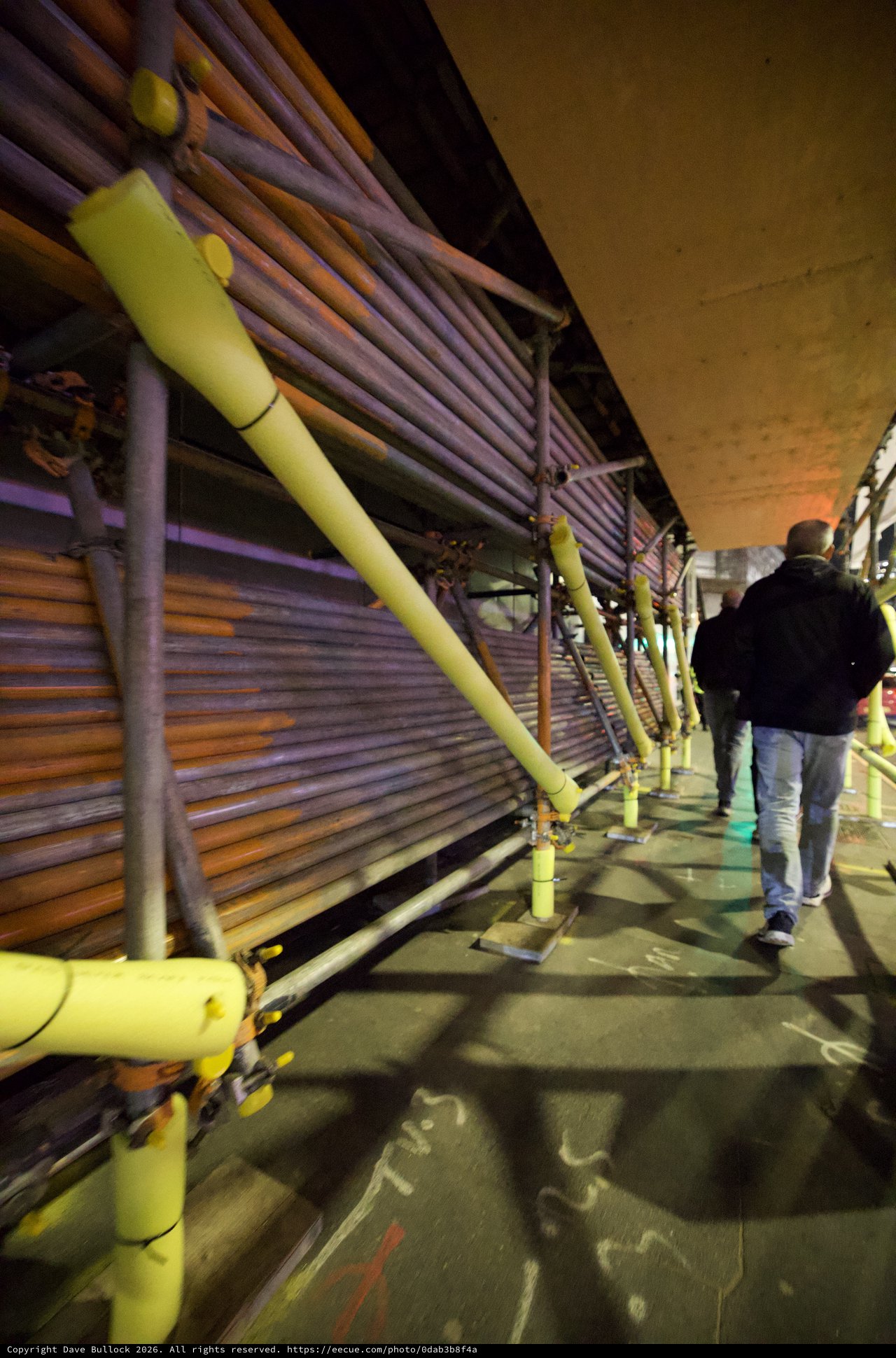 Evening Walk Under Urban Infrastructure with Yellow Safety Rails