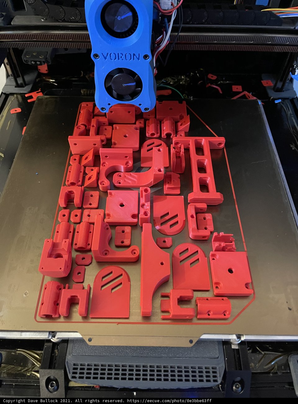 Red plastic car model being printed by 3D printer