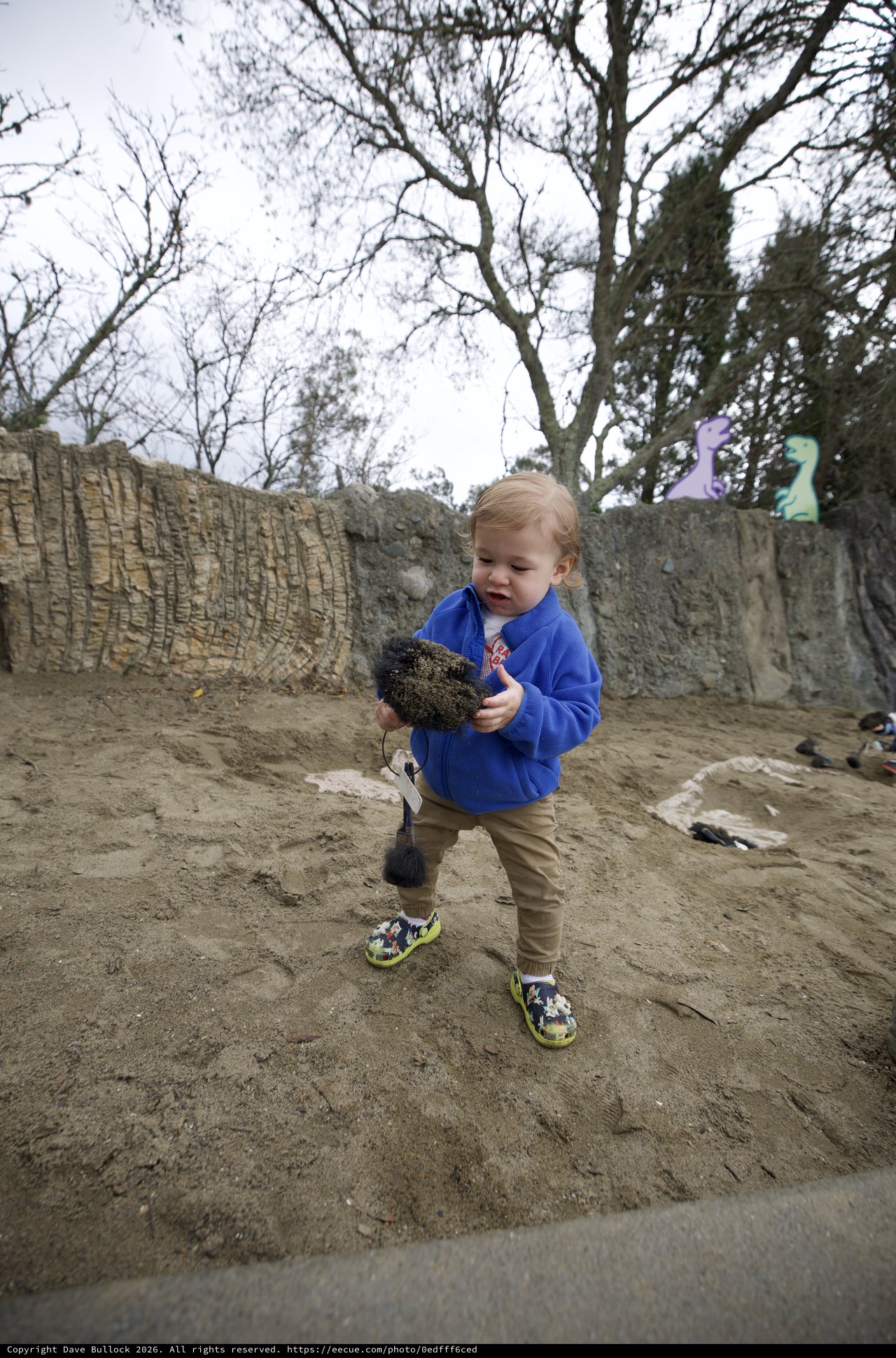 Toddler Exploring Sandy Play Area with Shovel