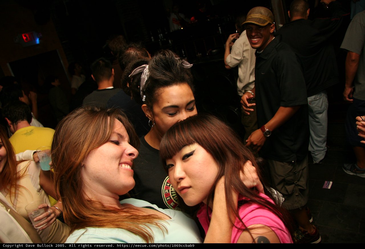 Three Friends Embracing on a Nightclub Dance Floor
