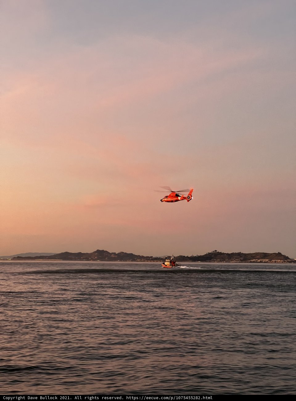 Helicopter Flying Over San Francisco Bay Caption: A stunning view from above as a helicopter soars over the ocean beside a boat enjoying the waters of San Francisco Bay at sunset.