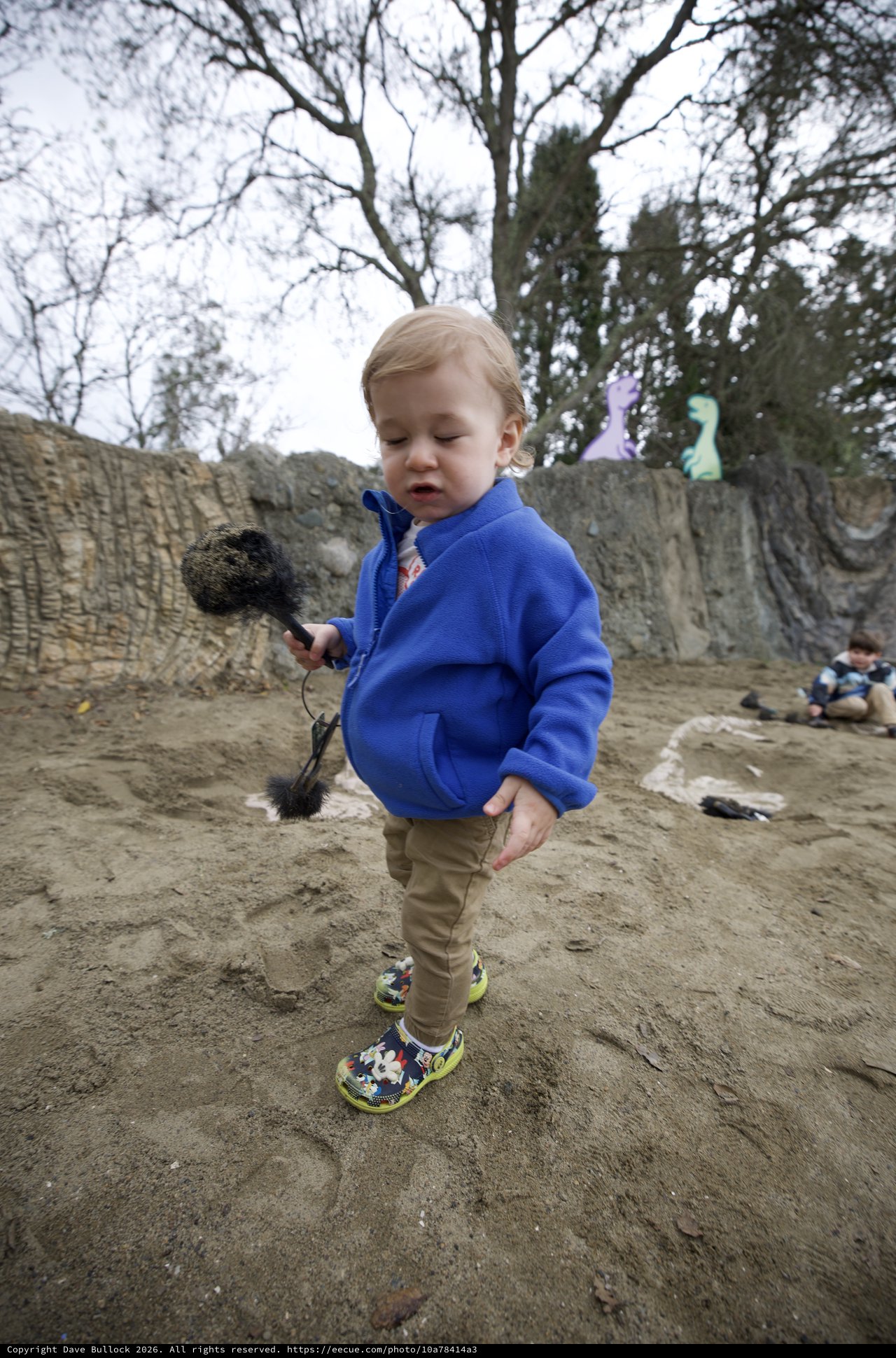 Toddler with Brush at Sandy Play Area