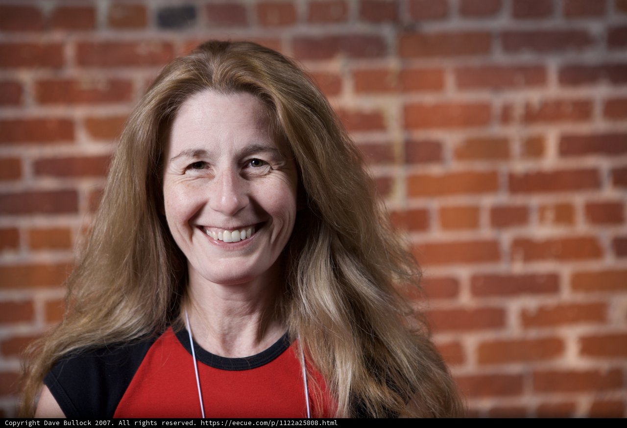 Red Shirted Woman Poses in Front of Brick Wall