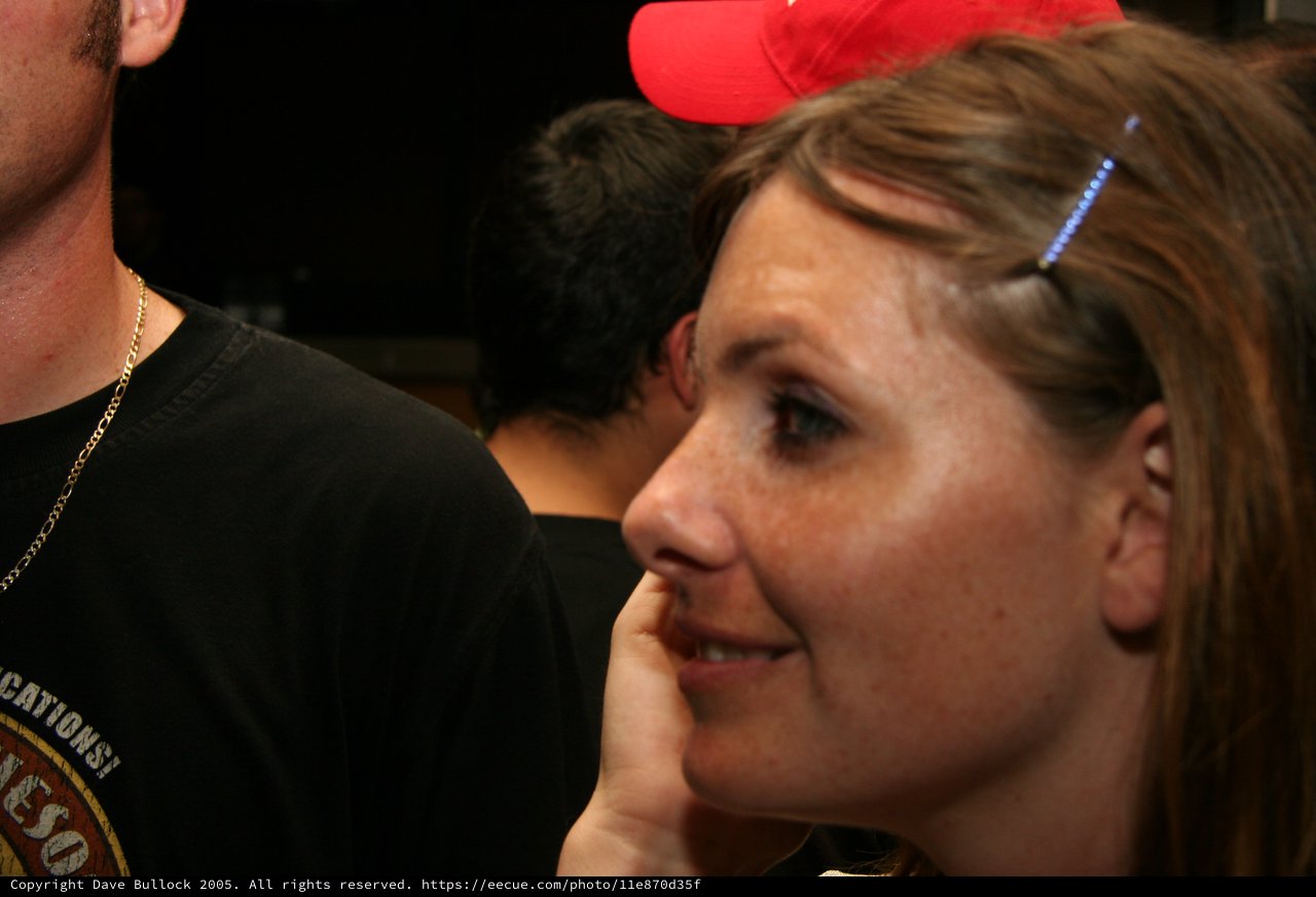 Woman in Red Cap Smiling at Indoor Gathering
