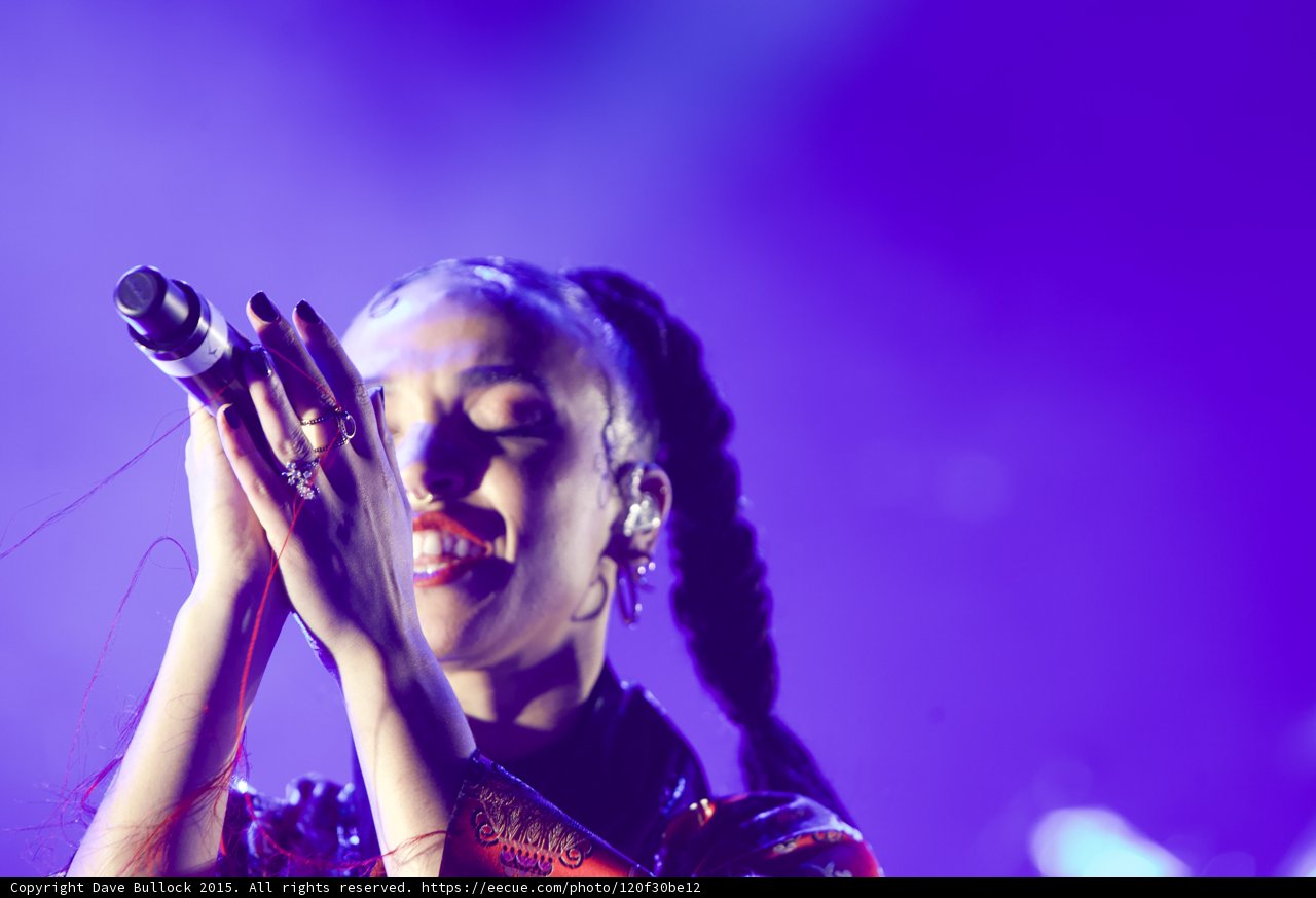 FKA twigs Joyful Portrait Eyes Closed Smiling Baby Hairs Hoop Earrings Red Lipstick Braided Ponytails Black Choker Both Hands Holding Microphone Rings Kimono Red Pattern Purple Blue Lighting