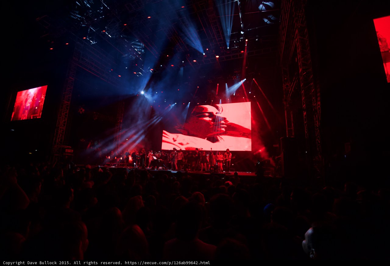 Belle and Sebastian Wide Stage Video Screen Woman Profile Red Lighting Spotlight Beams Ensemble