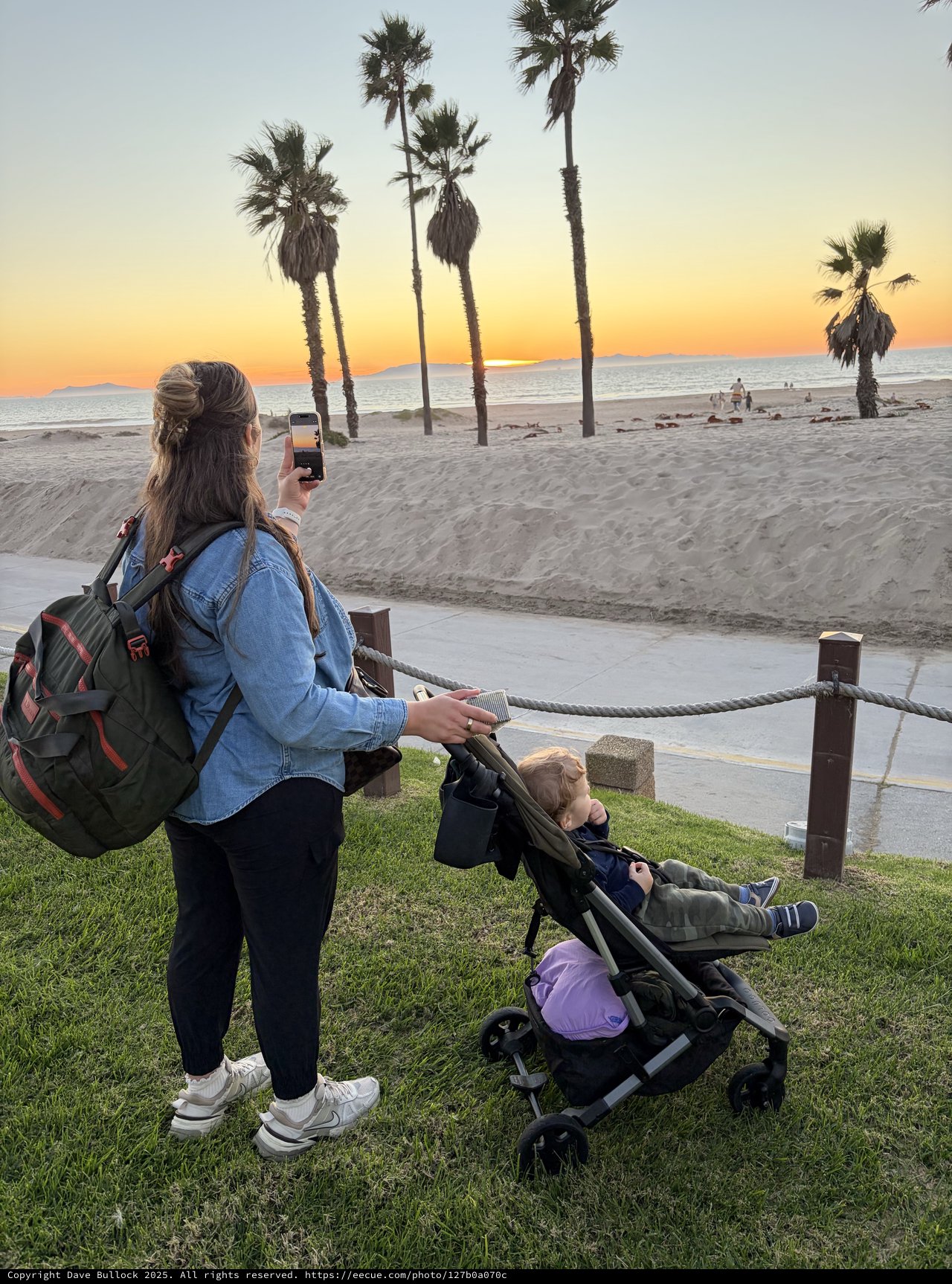 Mother Capturing Sunset Moment with Child at Beach