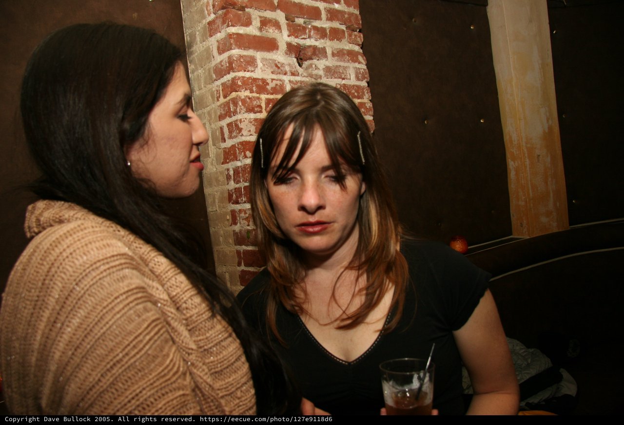 Two Women Conversing at a Dimly Lit Bar